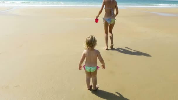 Мама и ребенок гуляют с ведром на пляже — стоковое видео