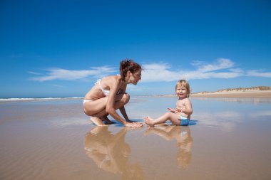 deniz kenarında oturan anne ve bebek