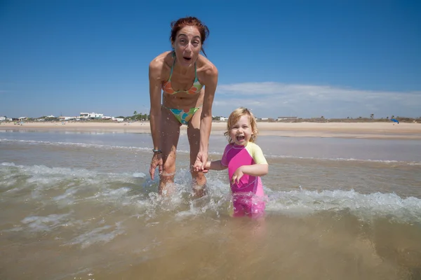 Laughing mother and baby at ocean — Stock Photo, Image