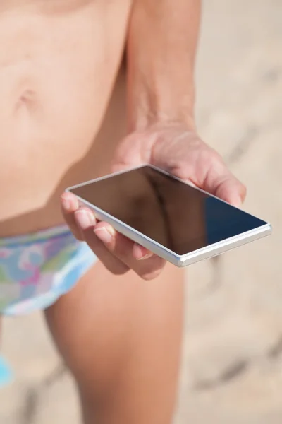 Mano de mujer con teléfono sobre arena — Foto de Stock