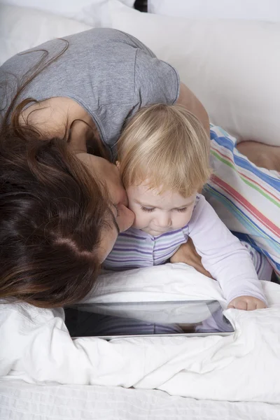 Mãe beijando bebê assistindo tablet — Fotografia de Stock