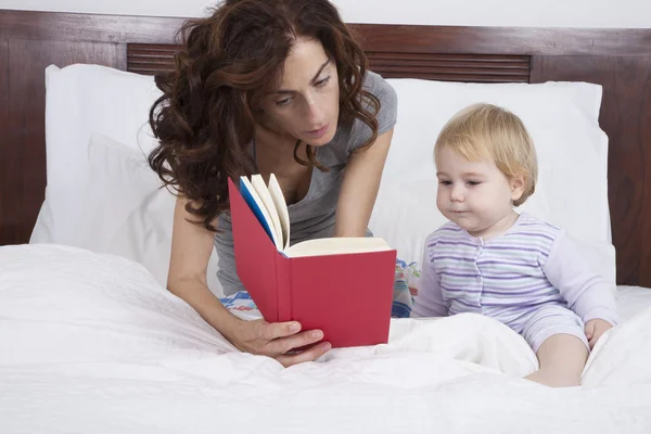 Mãe e bebê lendo na cama — Fotografia de Stock