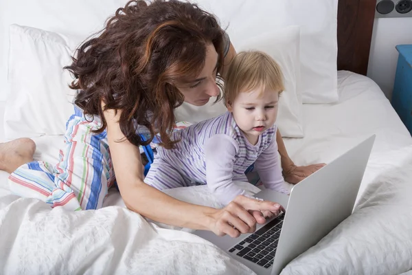 Mom baby and laptop on bed — Stock Photo, Image