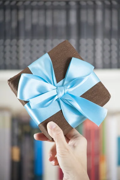 Showing brown present box over library — Stock Photo, Image