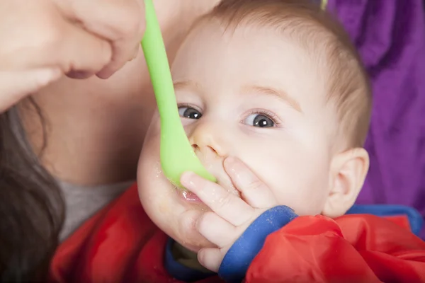 Hand feeding in green plastic spoon — Stock Photo, Image