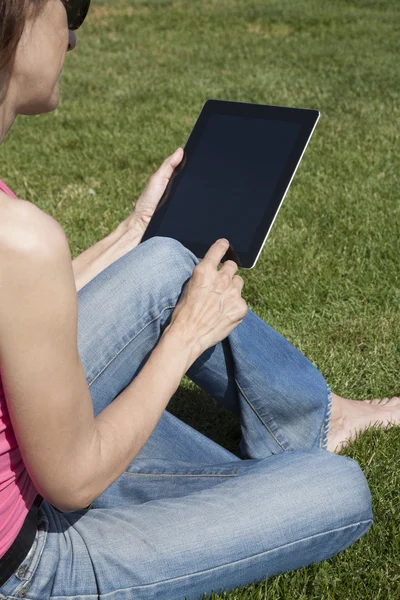 Tablet in woman hands on grass — Stock Photo, Image