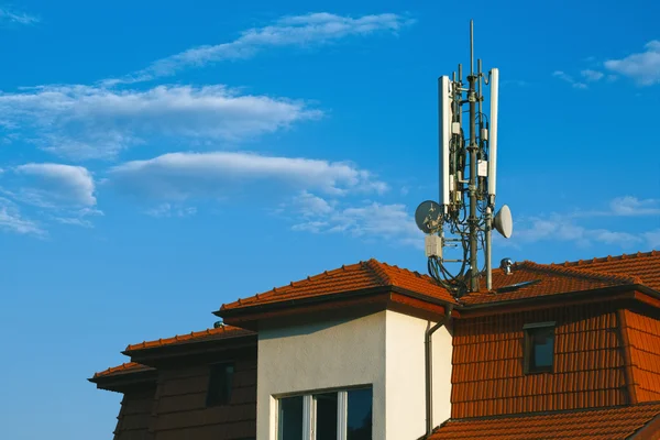 Edifício vivo com antenas GSM no telhado isolado no céu azul — Fotografia de Stock