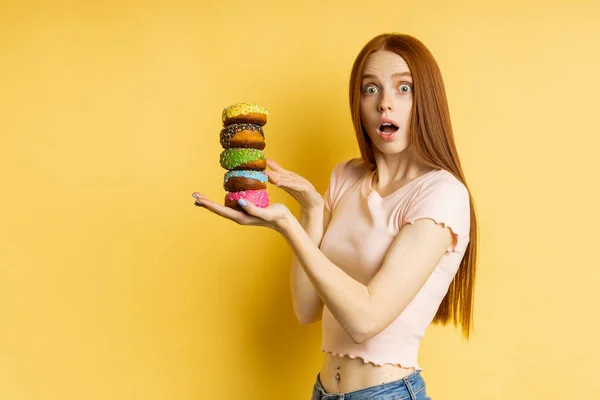 Sarı arka planda donutları olan genç ve güzel bir kadın. — Stok fotoğraf