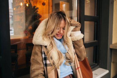 Güzel sarışın kız üşümüş, kış günü kendini şehrin dondurucusundan korumaya çalışıyor. Genç, beyaz bir kadın sokakta arkadaşını bekliyor. Soğuk hava konsepti.