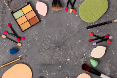 Güzel kozmetik çerçeveli fırçalar, aplikatörler, gölgeler ve kalemler. Gri arka planda fotokopi alanı var. makyaj, güzellik, moda, gençlik, bakım konsepti