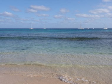 Kum plajı ve Atlantik Okyanusu 'ndaki tekneler Afrika Santa Maria kasabasında Cape Verde' deki Sal Adası 'nda, açık mavi gökyüzü 2019' da güneşli bir bahar günü Mart ayında.