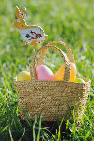 Barvená velikonoční vajíčka v košíku zaplněny králík dekorace — Stock fotografie