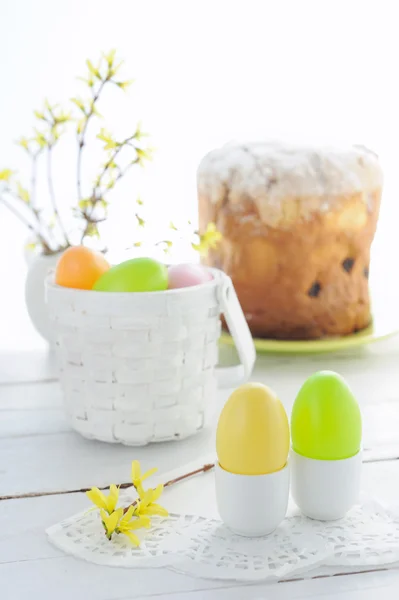 Easter eggs, holiday cake and flowering branches on wooden table — Stock Photo, Image