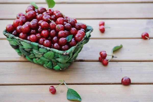 Ripe cherries in a basket on wooden table outdoor — Stock Photo, Image