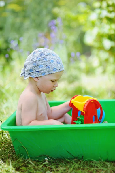 Liten söt pojke spelar i ett badkar i trädgården — Stockfoto