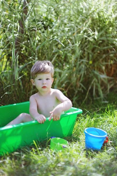 Pequeño niño lindo jugando en una bañera en el jardín — Foto de Stock