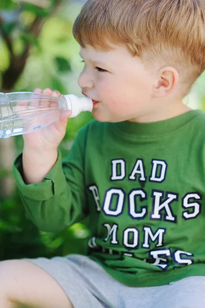 Atractivo niño bebiendo agua de la botella al aire libre — Foto de Stock