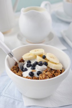 Yoğurt, taze çilek ve muz seramik kase ile bal granola