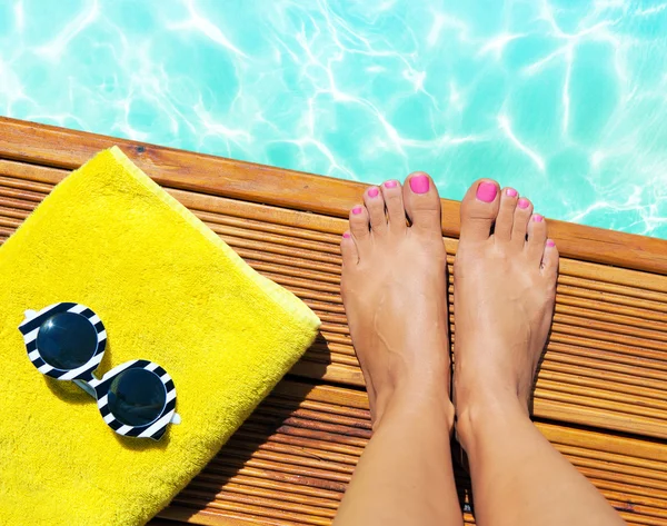 Mujer en un muelle de madera en la piscina con accesorios de verano — Foto de Stock