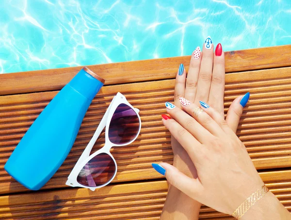 Mulher com unhas de gel segurando óculos de sol e protetor solar loção — Fotografia de Stock