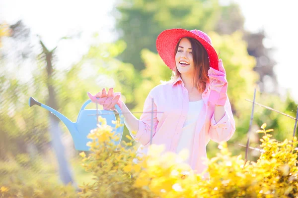 Vrouw met gieter in de tuin — Stockfoto