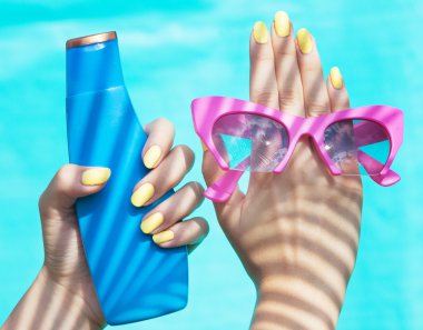 güneş gözlüğü ve güneş koruyucu losyon tutan kadın