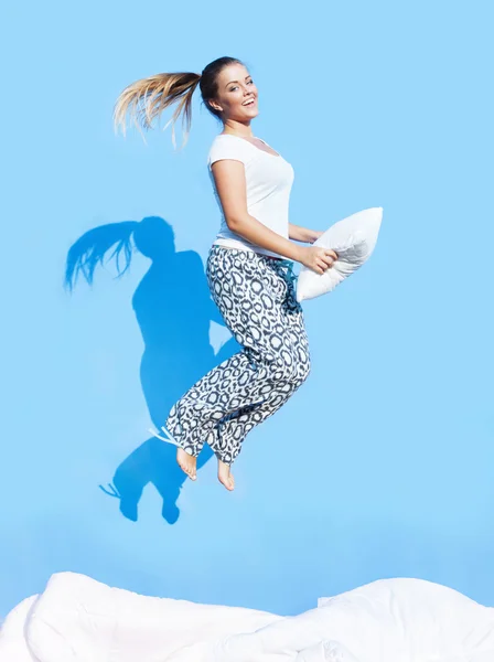 Frau mit Kopfkissen springt auf Bett auf — Stockfoto