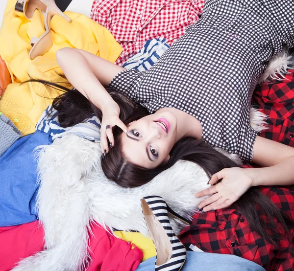 Mulher deitada em uma pilha de roupas — Fotografia de Stock