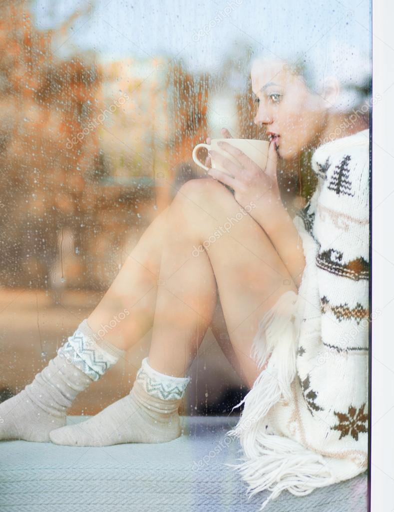 woman with cup sitting by the window