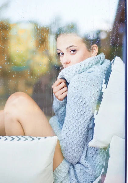 Brunette vrouw zitten achter een venster — Stockfoto