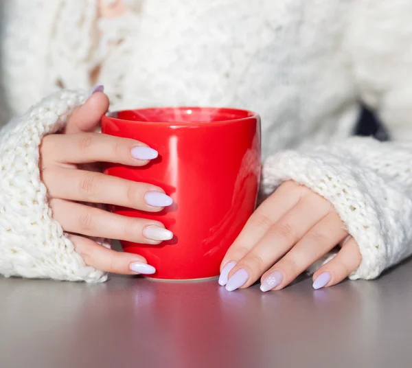 Mãos de mulher segurando xícara de bebida de café quente — Fotografia de Stock