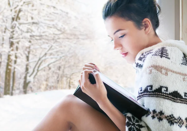 Mujer leyendo libro sentado junto a la ventana — Foto de Stock