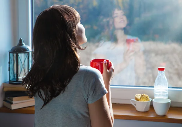 Mulher com xícara de café pela janela — Fotografia de Stock