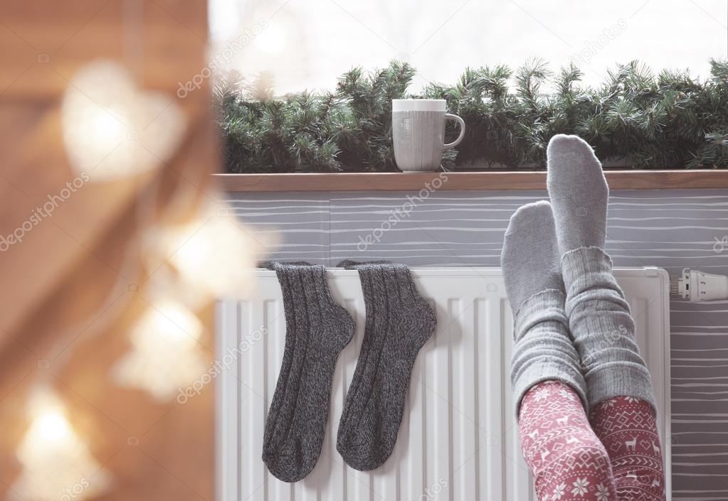 Woman warming up with feet on heater