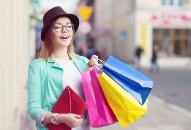 Şapka ve gözlük alışveriş torbaları tutan genç çekici alışveriş kadın