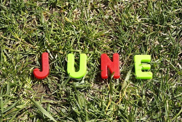 June letters from plastic on a background of green grass lie on the grass — Stock Photo, Image