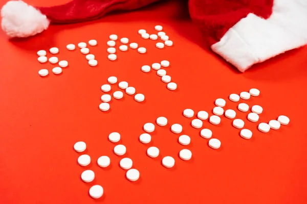 Stay home lettering from round white pills on a red background. Santa hat. High quality photo