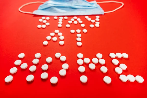 Stay home lettering from round white pills on a red background. face mask — Stock Photo, Image