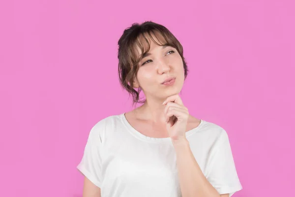 Tecrit edilmiş pembe arka planı olan bir kız bir fikir düşünüyor. Yüksek kalite fotoğraf