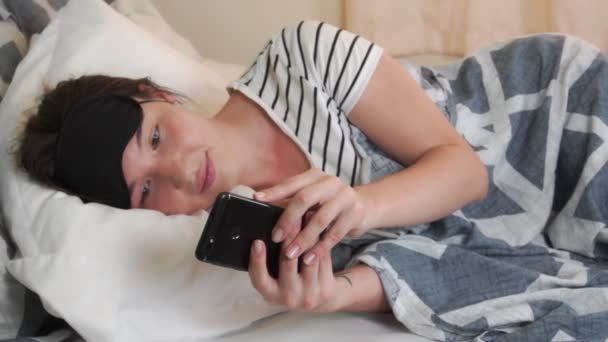 Attractive Young Woman Sleep Mask Chats Cell Phone While Lying — Vídeo de stock