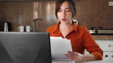 Genç bir melez kadın evde mutfakta oturuyor ve bilgisayar ekranına bakarken video aracılığıyla iletişim kuruyor. Bir kadın işte ya da uzaktaki bir sınıfta iletişim kurar..