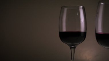 Kırmızı şarap, iki bardakta bir masada, koyu bir arka planda. Yavaş çekim orta çekim. Yüksek kaliteli FullHD görüntüler