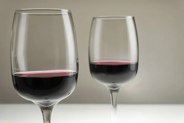 Zwei Gläser Rotwein auf verschwommenem homogenem Hintergrund. — Stockfoto