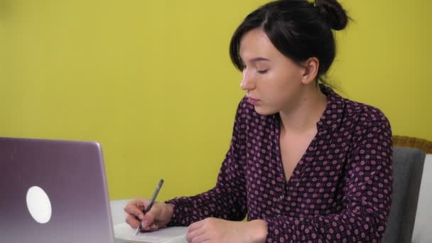 Een jonge gemengde ras vrouw zit thuis en is online bezig op een laptop. — Stockvideo