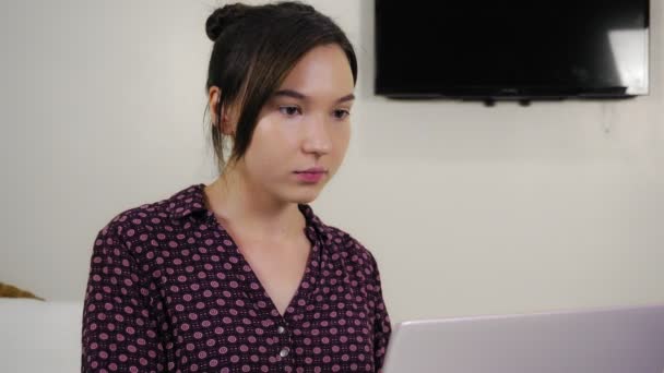 Νεαρή γυναίκα μικτή φυλή δακτυλογράφηση σε φορητό υπολογιστή, ενώ κάθεται στο γραφείο στο σπίτι. — Αρχείο Βίντεο