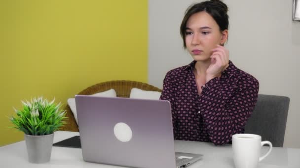 Молода змішана раса жінка друкує на ноутбуці, сидячи в домашньому офісі . — стокове відео