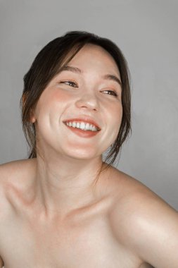 Mükemmel ciltli, zarif makyajlı melez bir kadın. Gri üzerine izole edilmiş gülümsüyor.. 