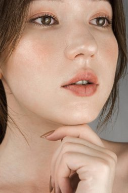 Mükemmel ciltli ve hassas makyajlı melez kadın griye bürünmüş.