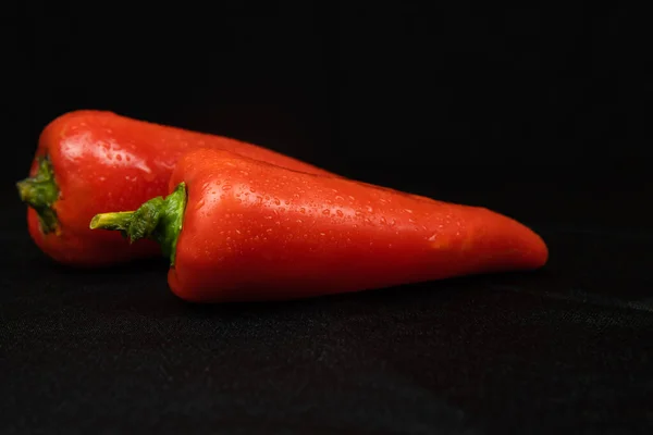 Pimenta vermelha em um fundo preto. Fundo de tecido preto em dobras. — Fotografia de Stock