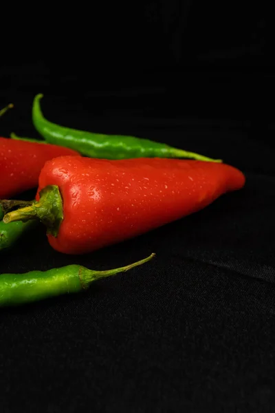 Rode Groene Pepers Een Zwarte Achtergrond Zwarte Stof Achtergrond Vouwen — Stockfoto